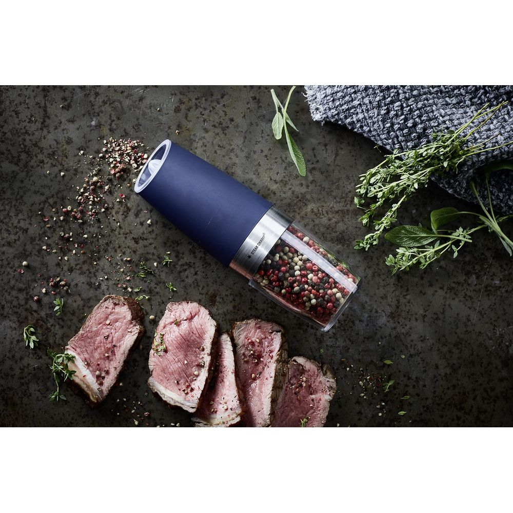 Scheiben rosa Roastbeef liegen neben einer blauen Pfeffermühle mit Pfefferkörnern.