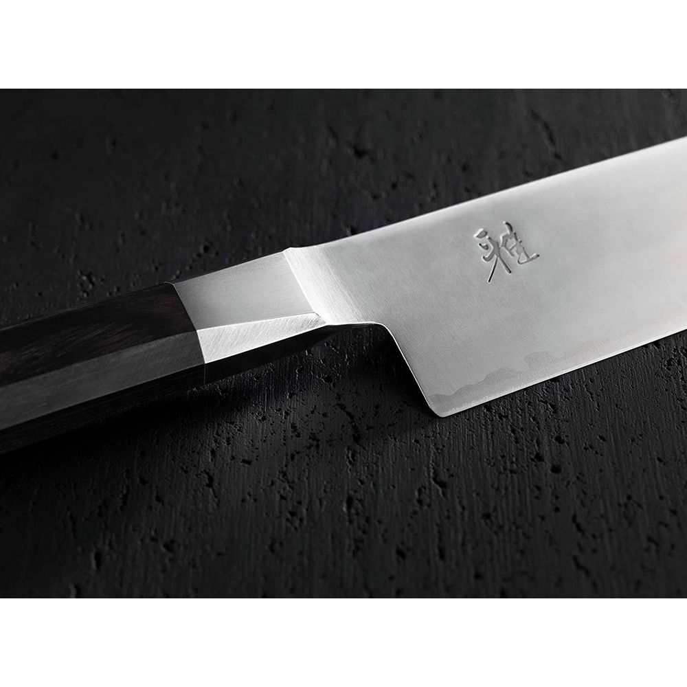 Ein silbernes Messer mit dunklem Griff liegt auf schwarzem Untergrund.