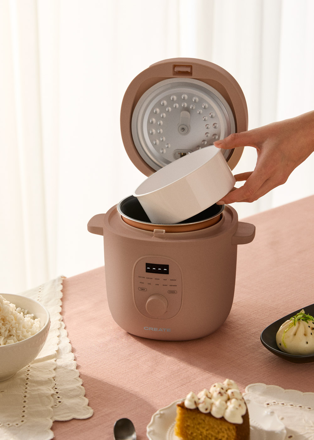 Una mano coloca un bol blanco en una olla de cocción lenta marrón. Hay arroz.