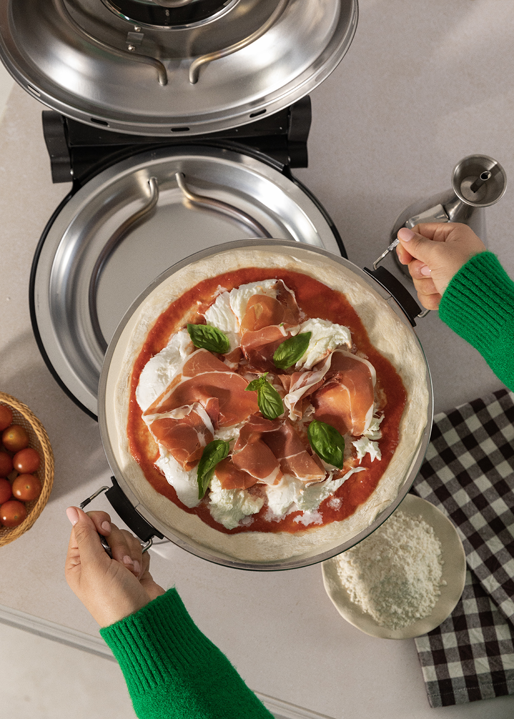 Una pizza cruda con prosciutto, mozzarella y albahaca se desliza en un horno de pizza.