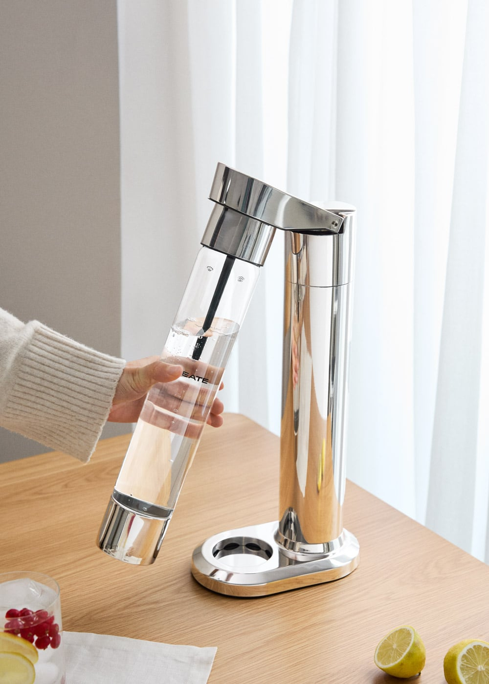 Máquina de soda plateada con botella transparente llena de agua.