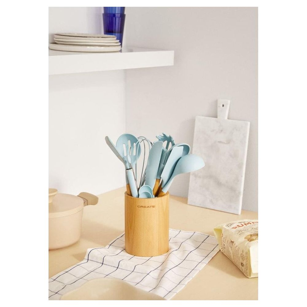 Utensilios de cocina azul claro en un soporte de madera sobre una servilleta.