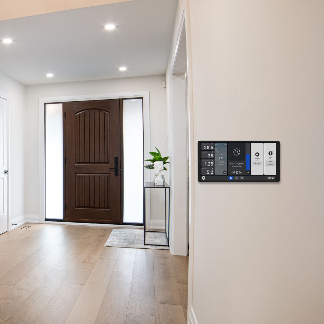 Pannello di controllo smart home su muro vicino porta in legno, mostra temp, ora e icone.