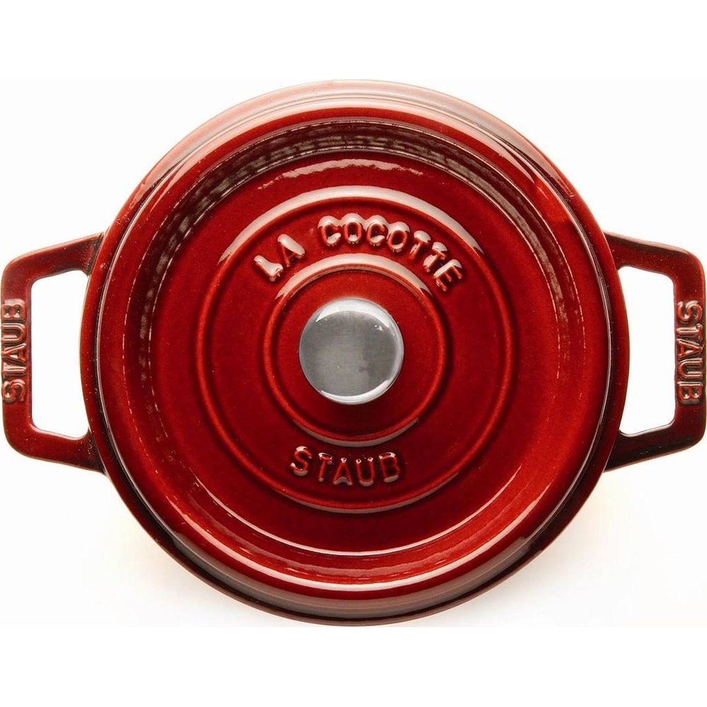 Eine rote Staub Cocotte mit silbernem Griff und Ringen.