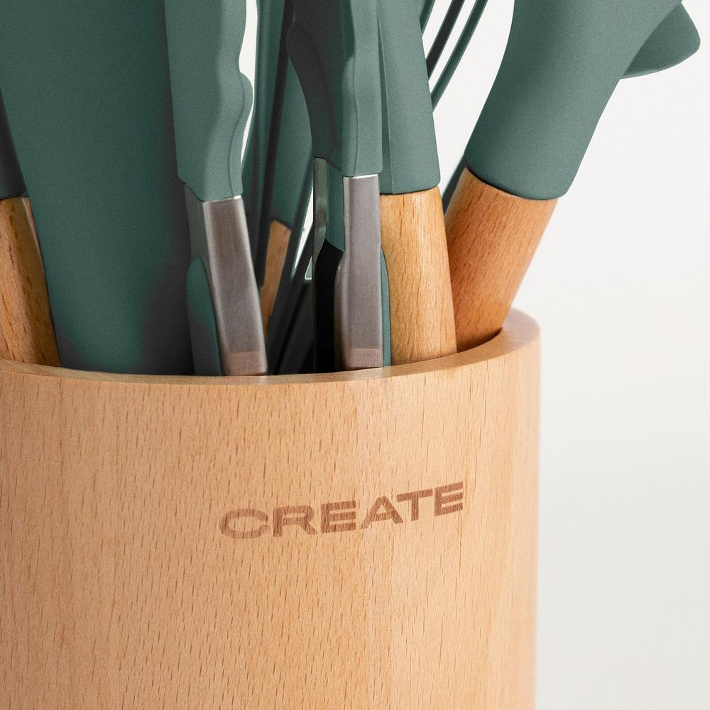 Utensilios de cocina verdes con mangos de madera en un soporte de madera con CREATE.