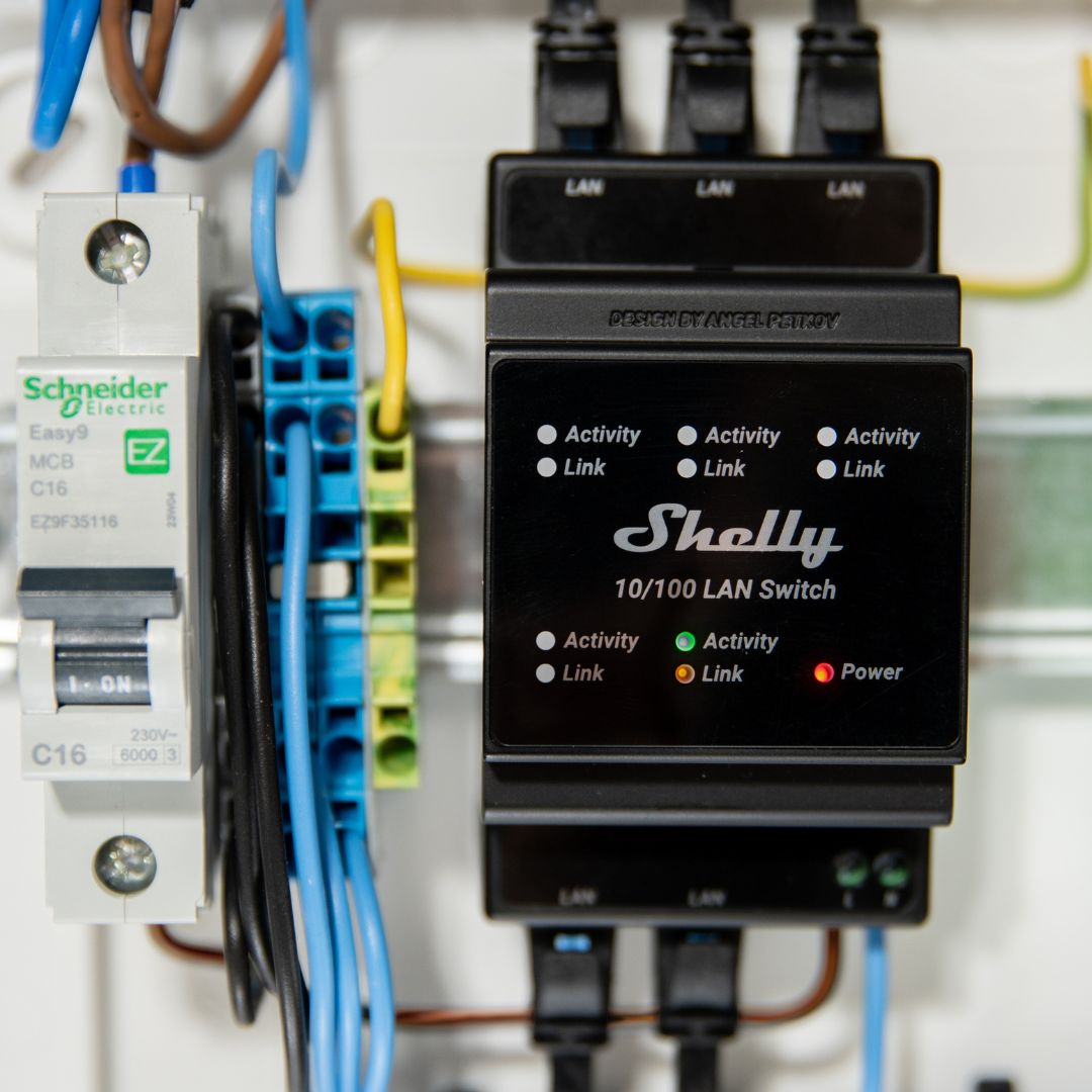 Przełącznik LAN Shelly z wyłącznikiem i przewodami w panelu elektrycznym.