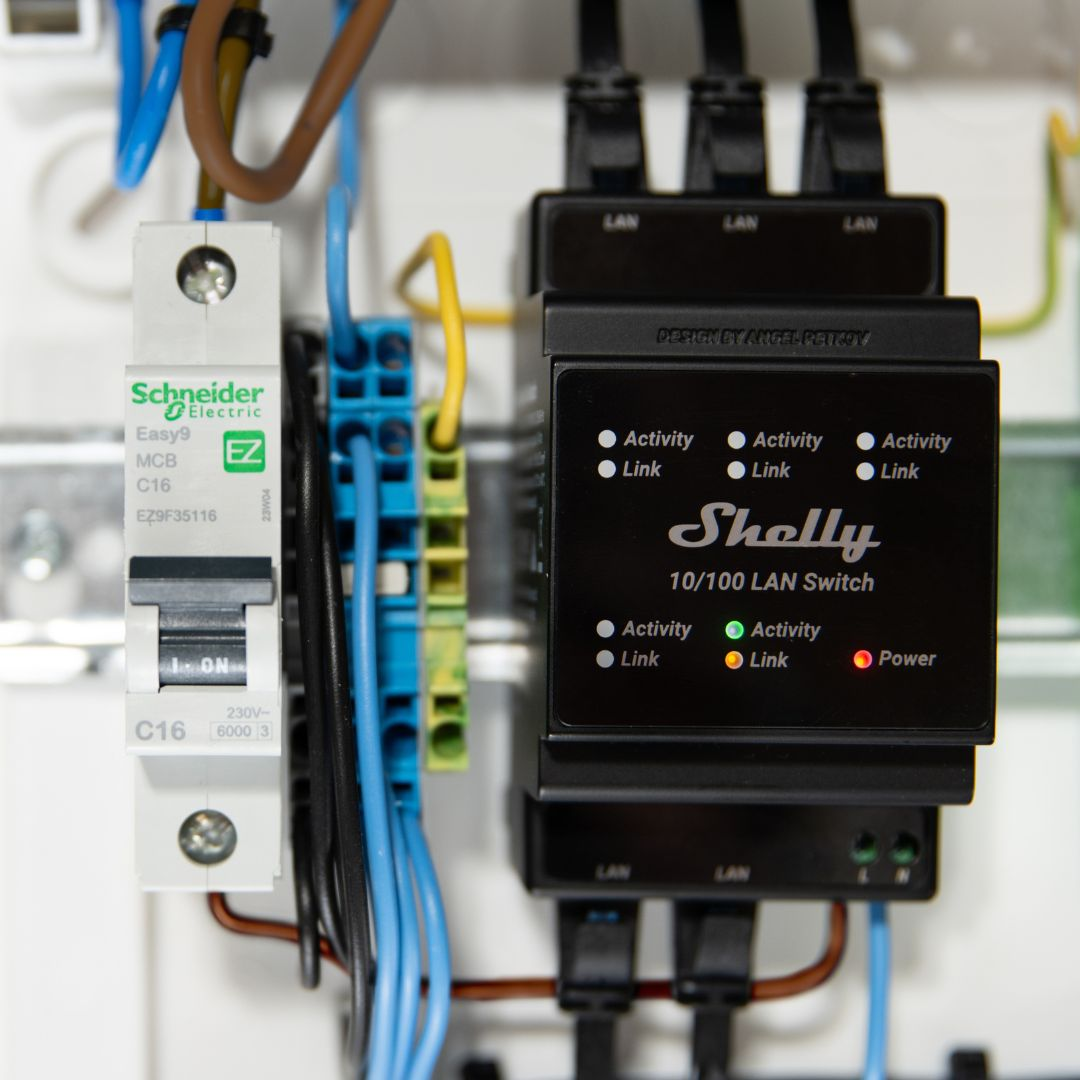 Un interruttore automatico elettrico e uno switch LAN Shelly con cavi.