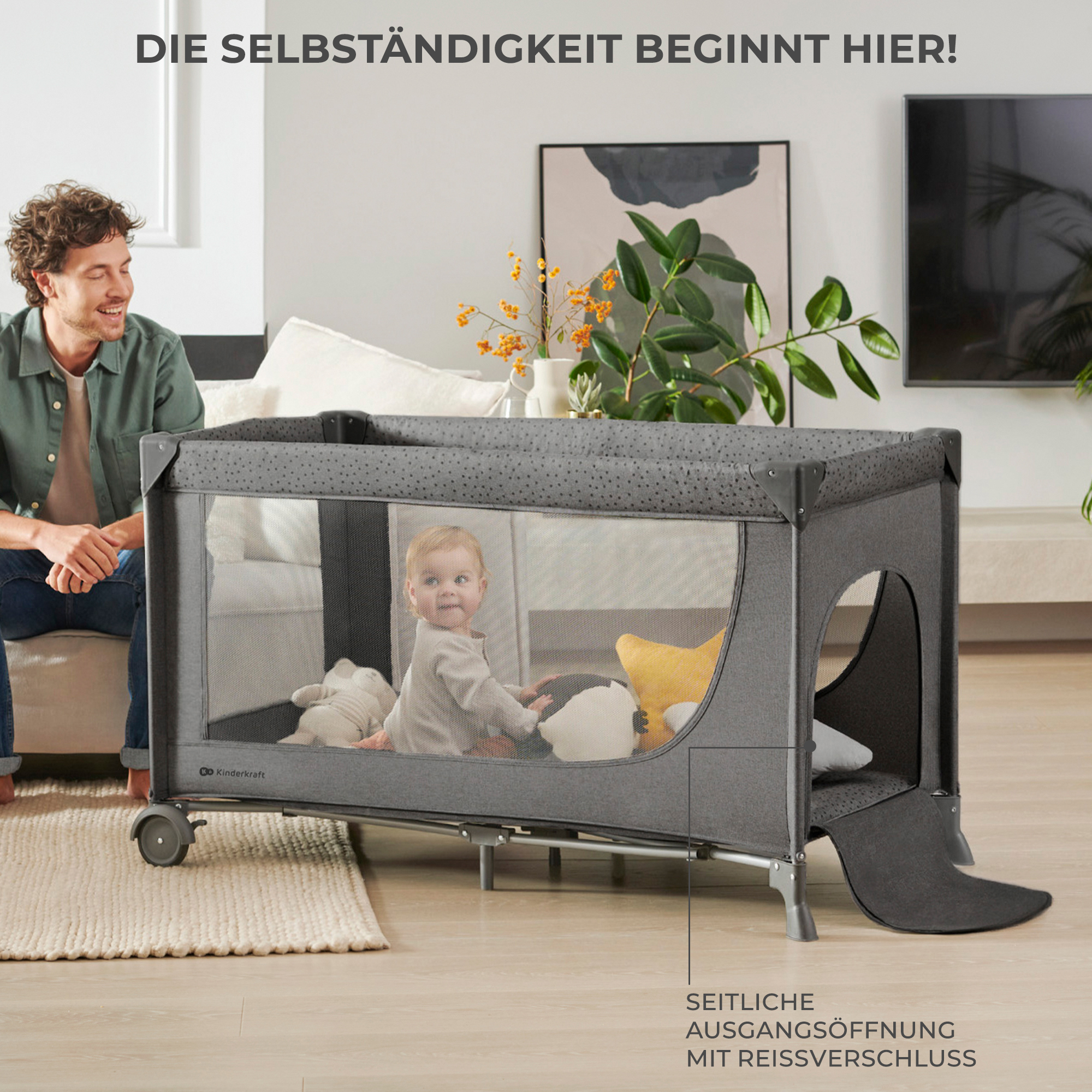 Ein Mann sitzt lächelnd auf dem Sofa, während ein Baby in einem Laufstall spielt.