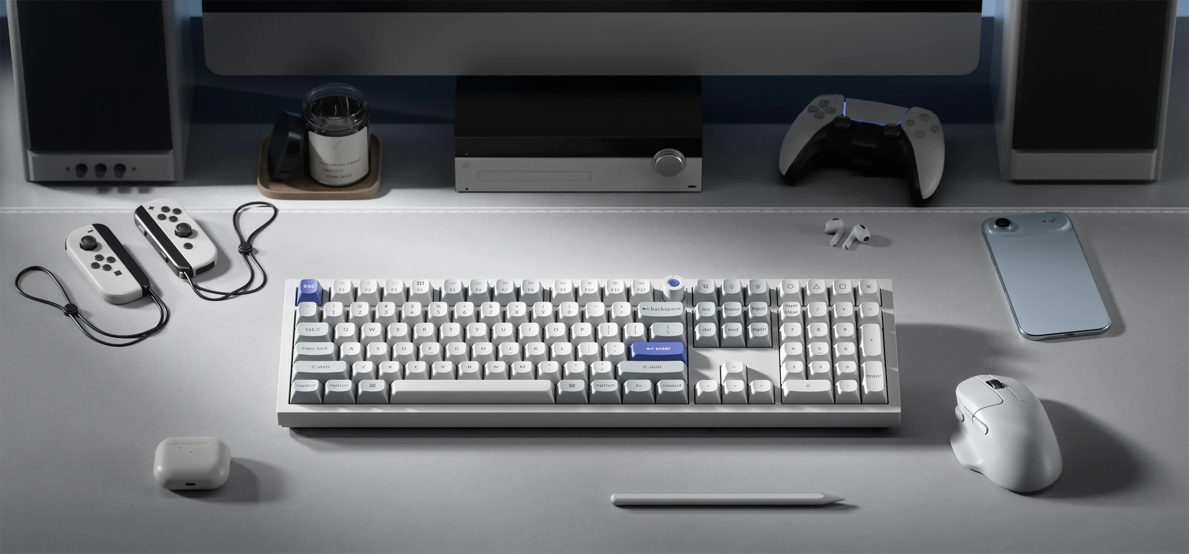Biała klawiatura, mysz, kontrolery i smartfon na szarej macie.