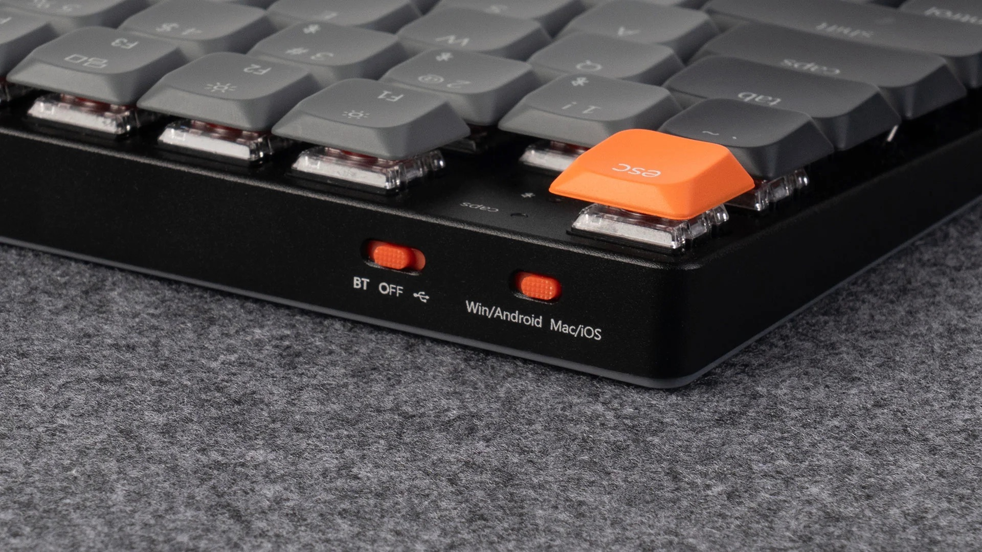 Szara klawiatura z pomarańczowym klawiszem ESC i przełącznikami.