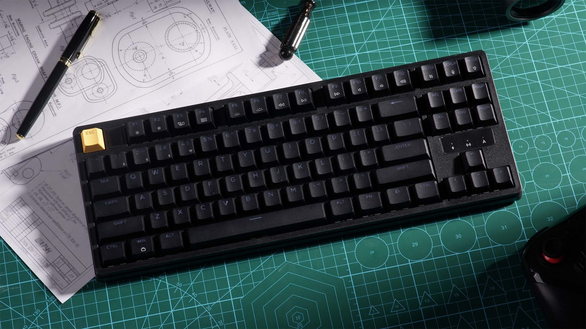 Czarna klawiatura z żółtym klawiszem ESC na rysunkach technicznych i macie tnącej.
