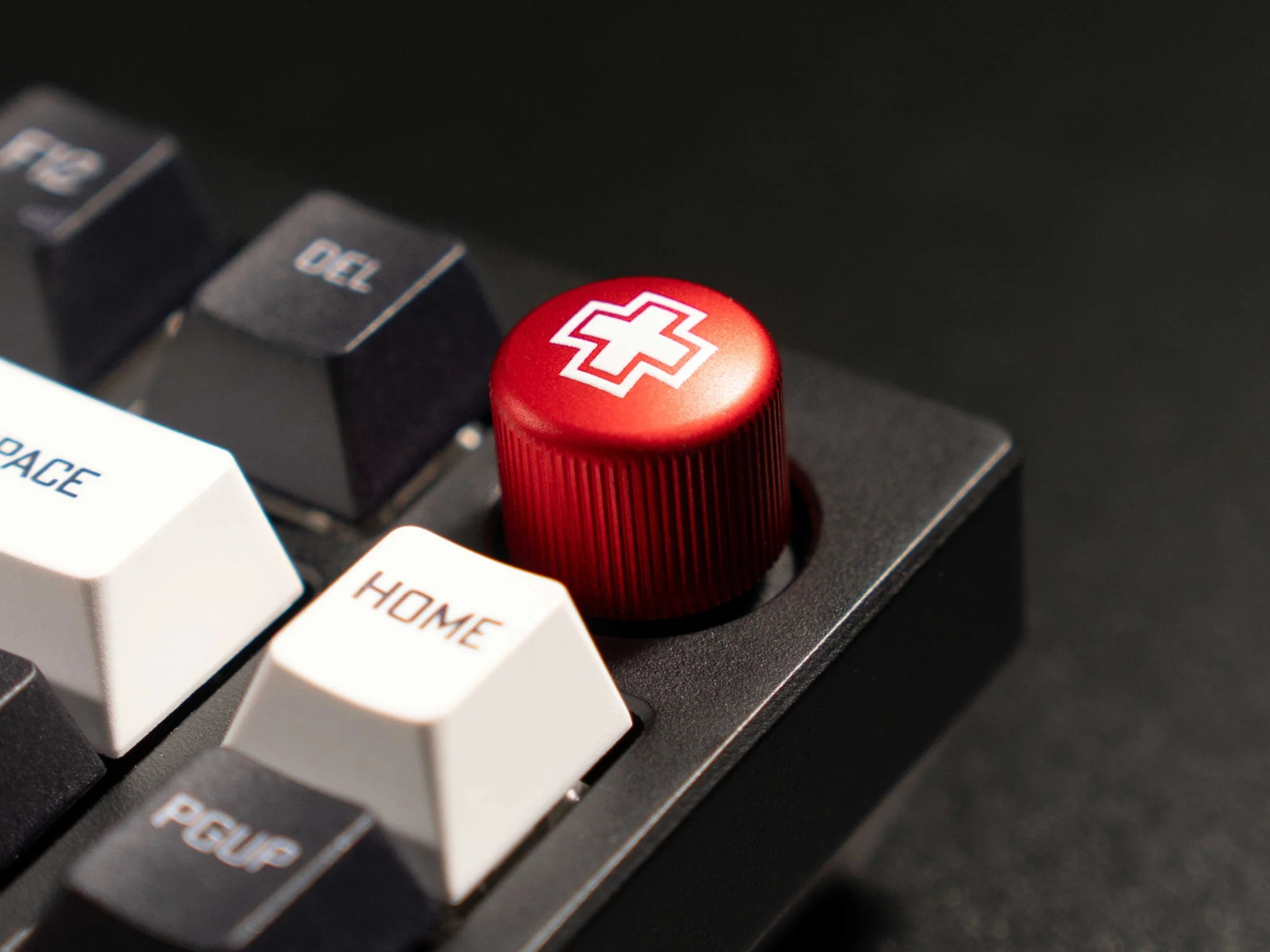 Czerwone pokrętło z białym symbolem krzyża na klawiaturze.
