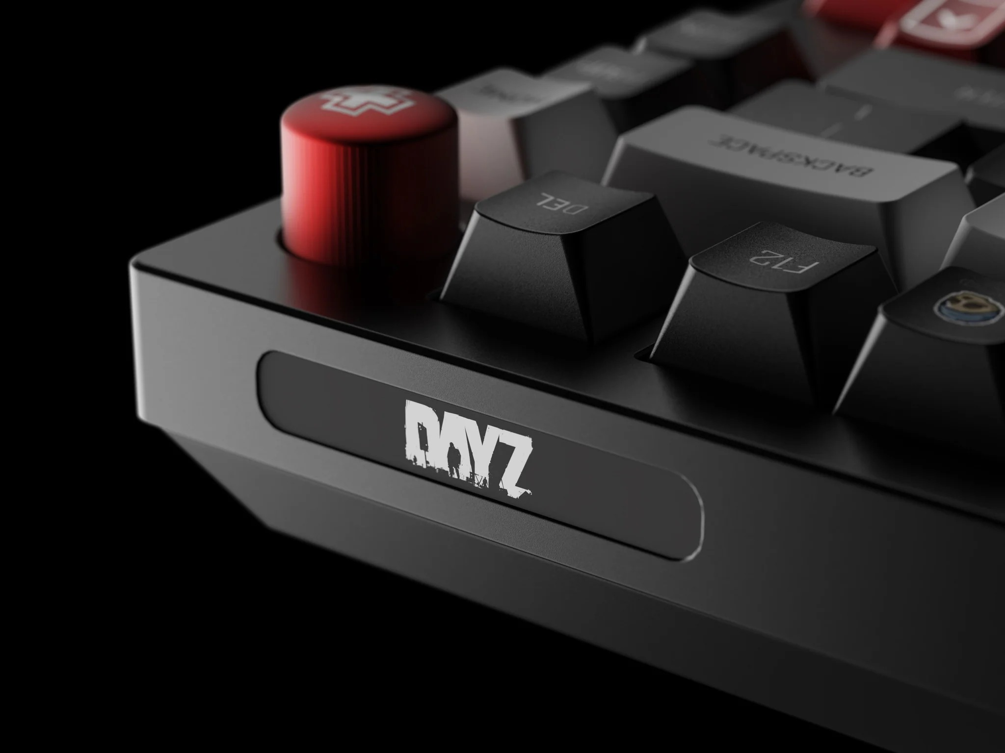 Czarna klawiatura z czerwonym pokrętłem i logo DayZ. Zbliżenie.
