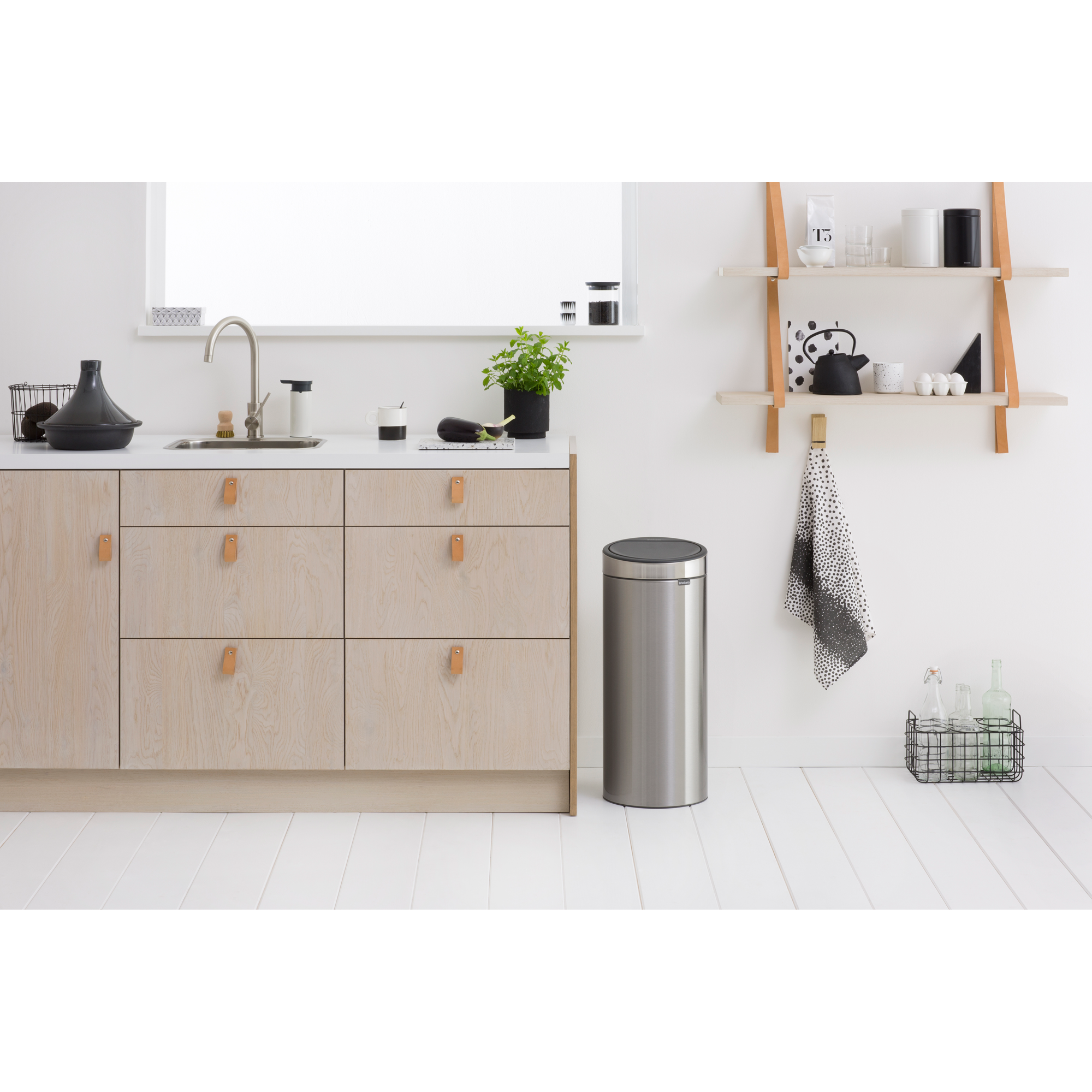 Modern kitchen with wooden cabinets, sink, and trash can.