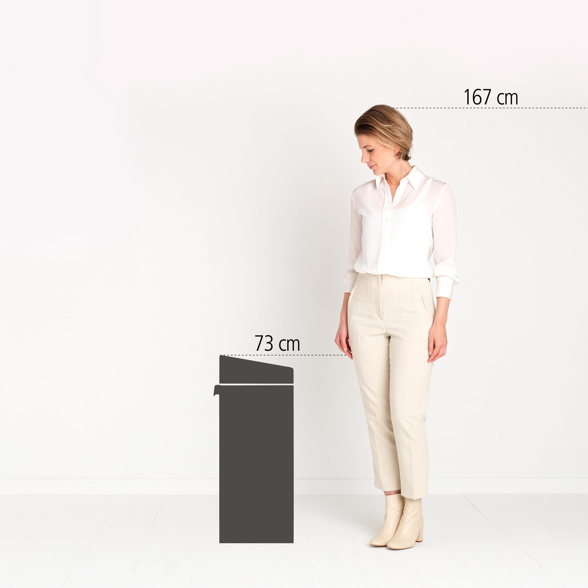 Een vrouw staat naast een donker object van 73 cm. Haar lengte is 167 cm.