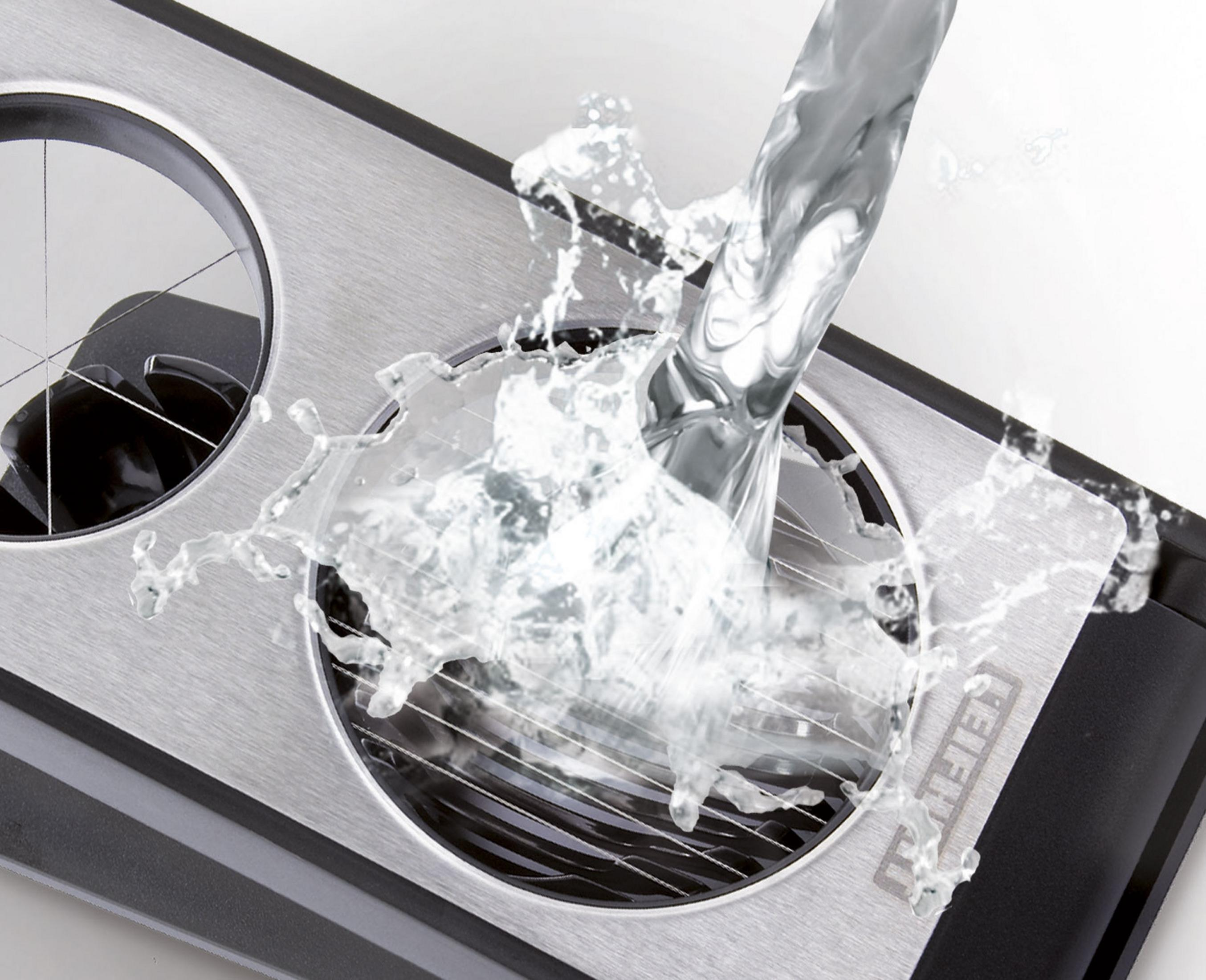 Wasser spritzt auf ein gebürstetes Metallgerät mit runden Öffnungen und schwarzen Akzenten.