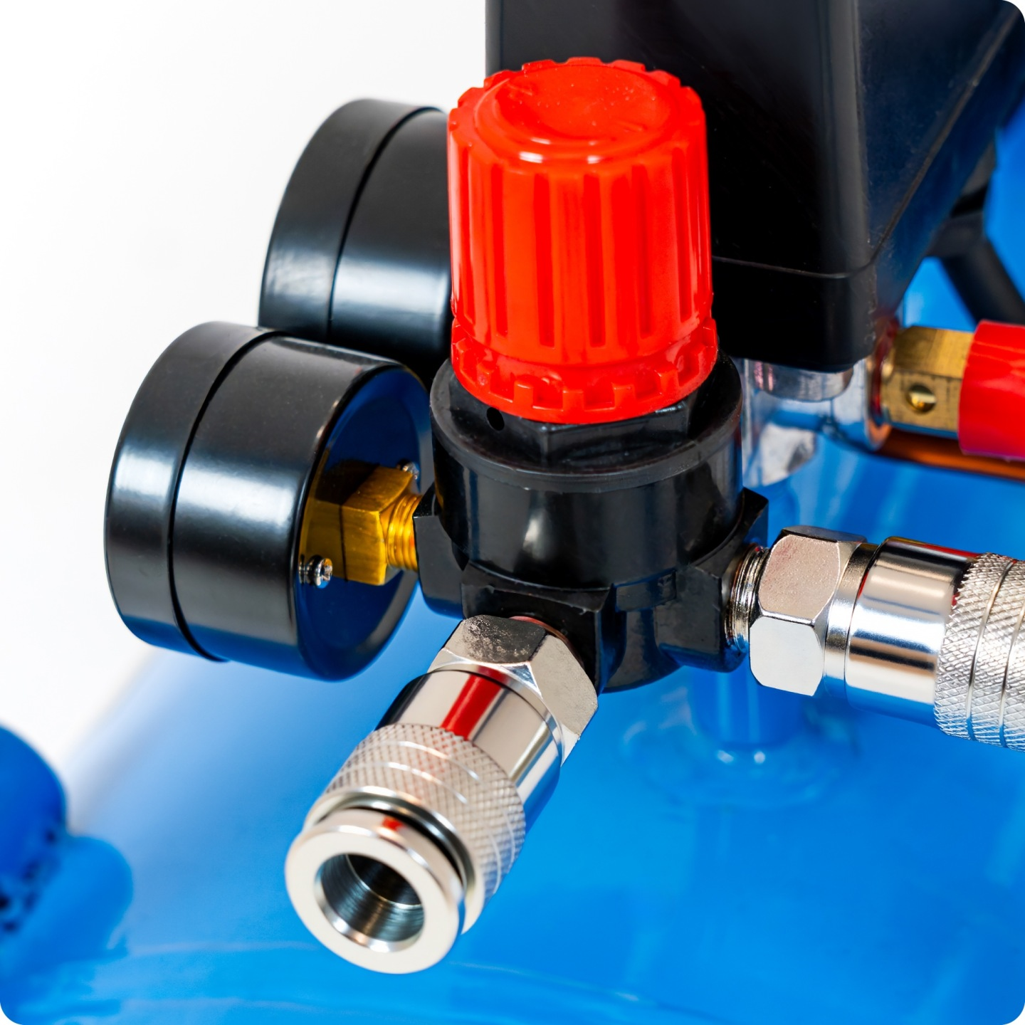 Zbliżenie niebieskiego kompresora powietrza z regulatorem ciśnienia, manometrami i szybkozłączką.