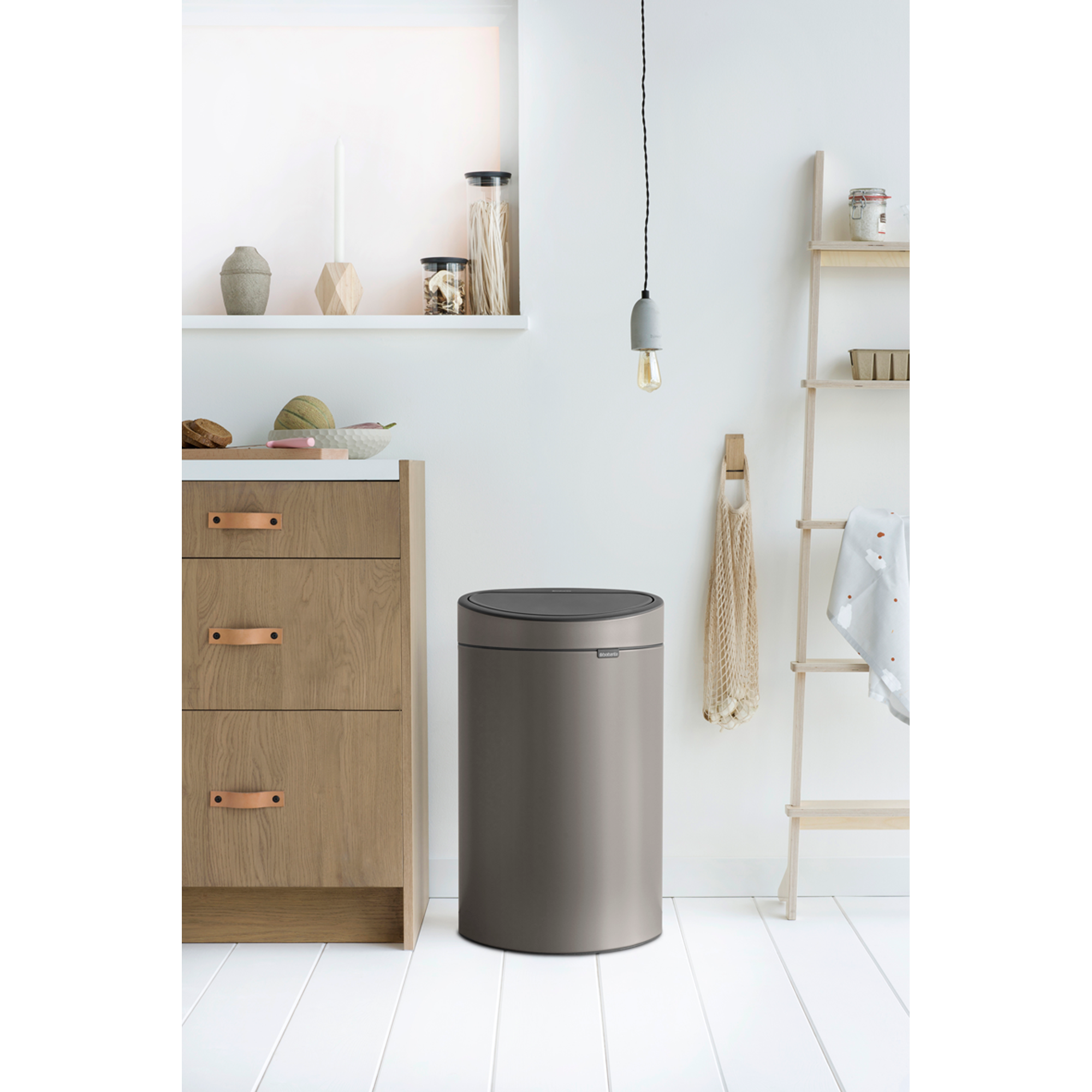 Gray trash can next to wooden cabinets and a ladder with a net.