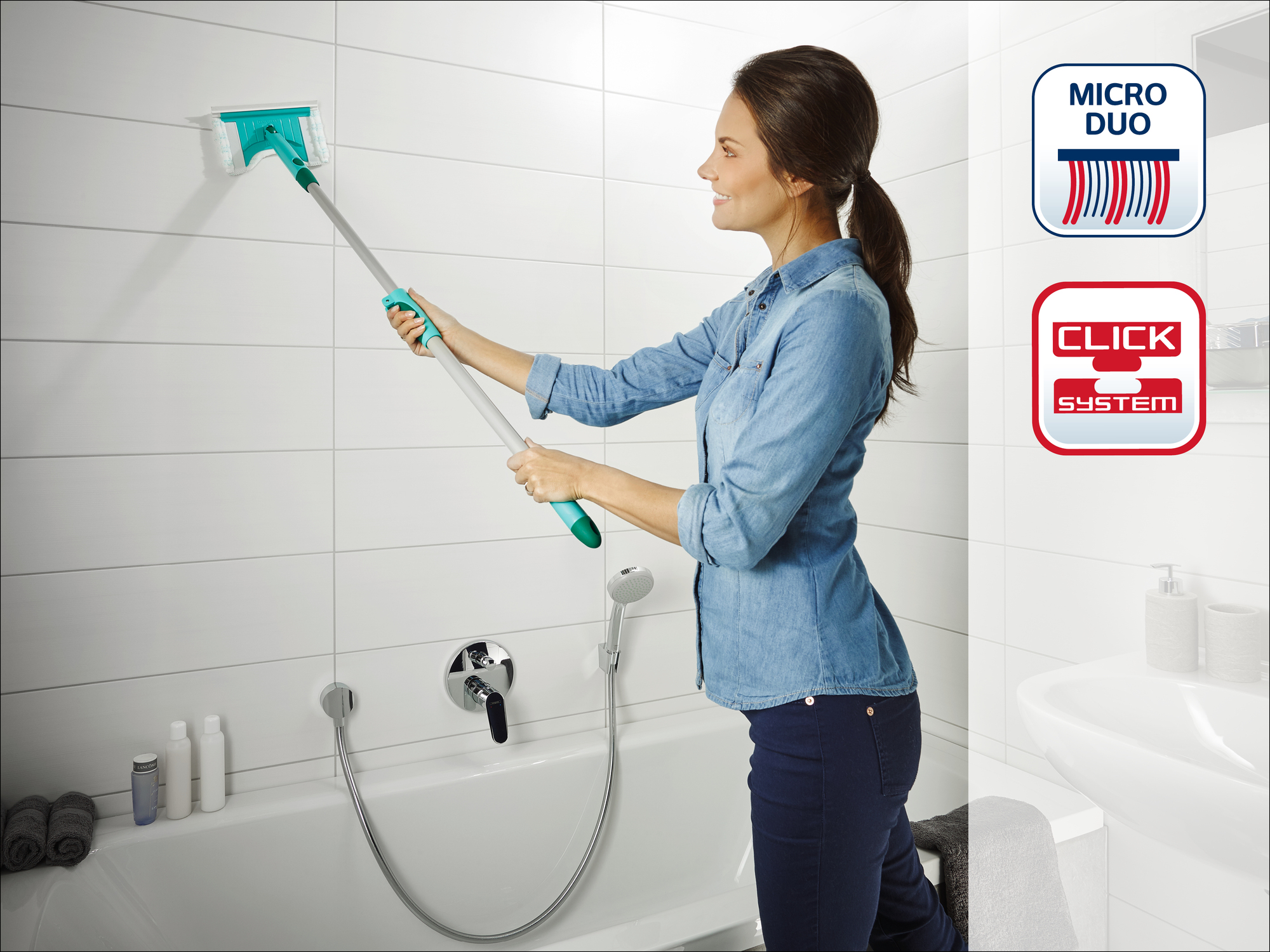 Frau reinigt weiße Wandfliesen mit einem Wischmopp neben der Badewanne.