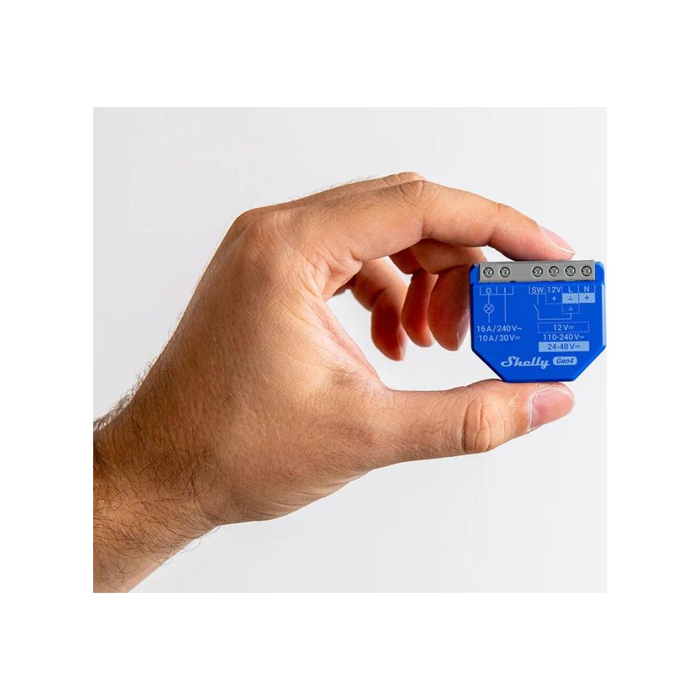 Una mano tiene un piccolo dispositivo blu Shelly Gen4 per la smart home.