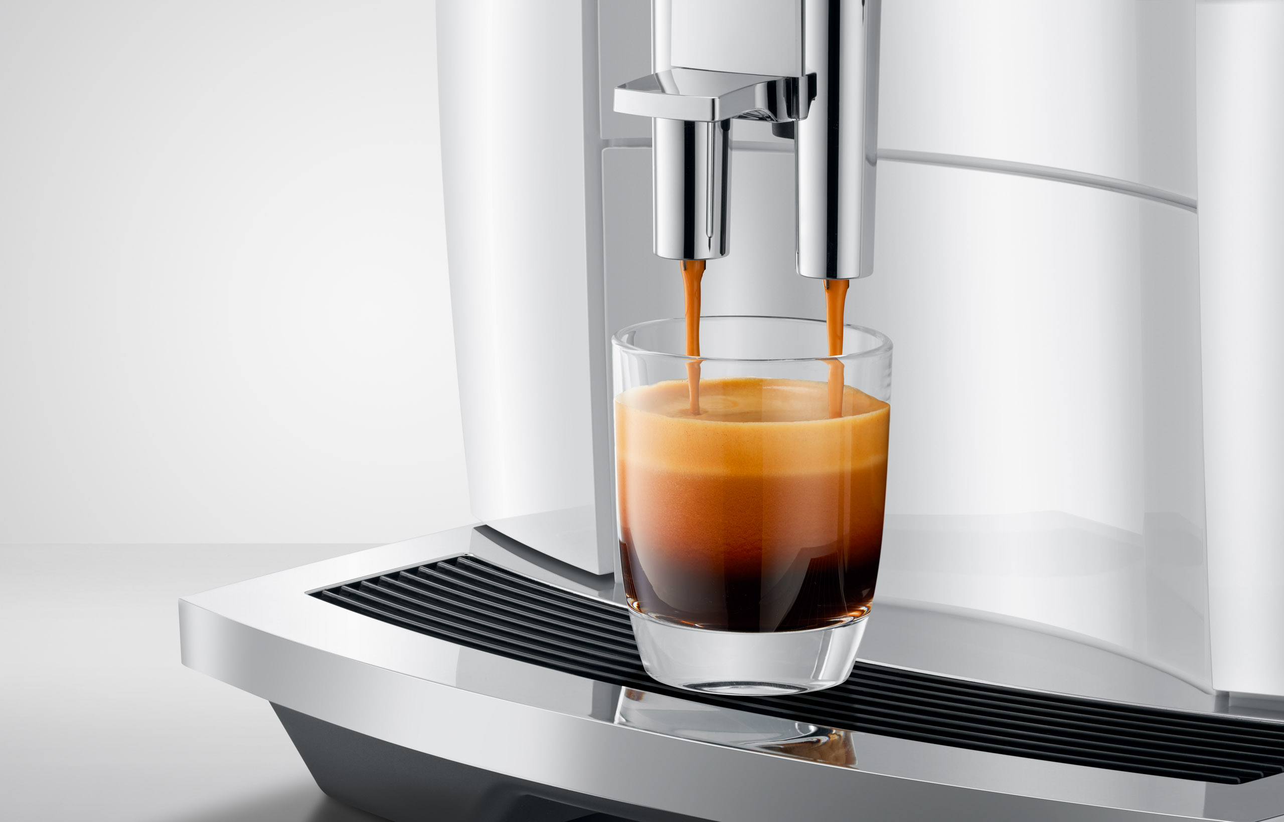 Ein Espresso wird in ein Glas gegossen, von einer Kaffeemaschine.