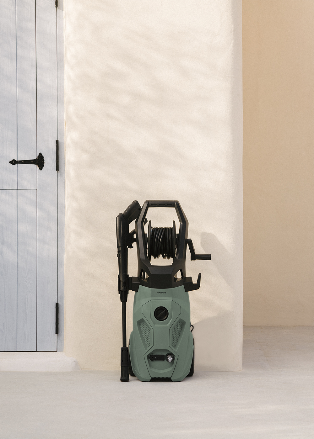 Una hidrolimpiadora verde junto a una puerta de madera blanca y una pared color crema.