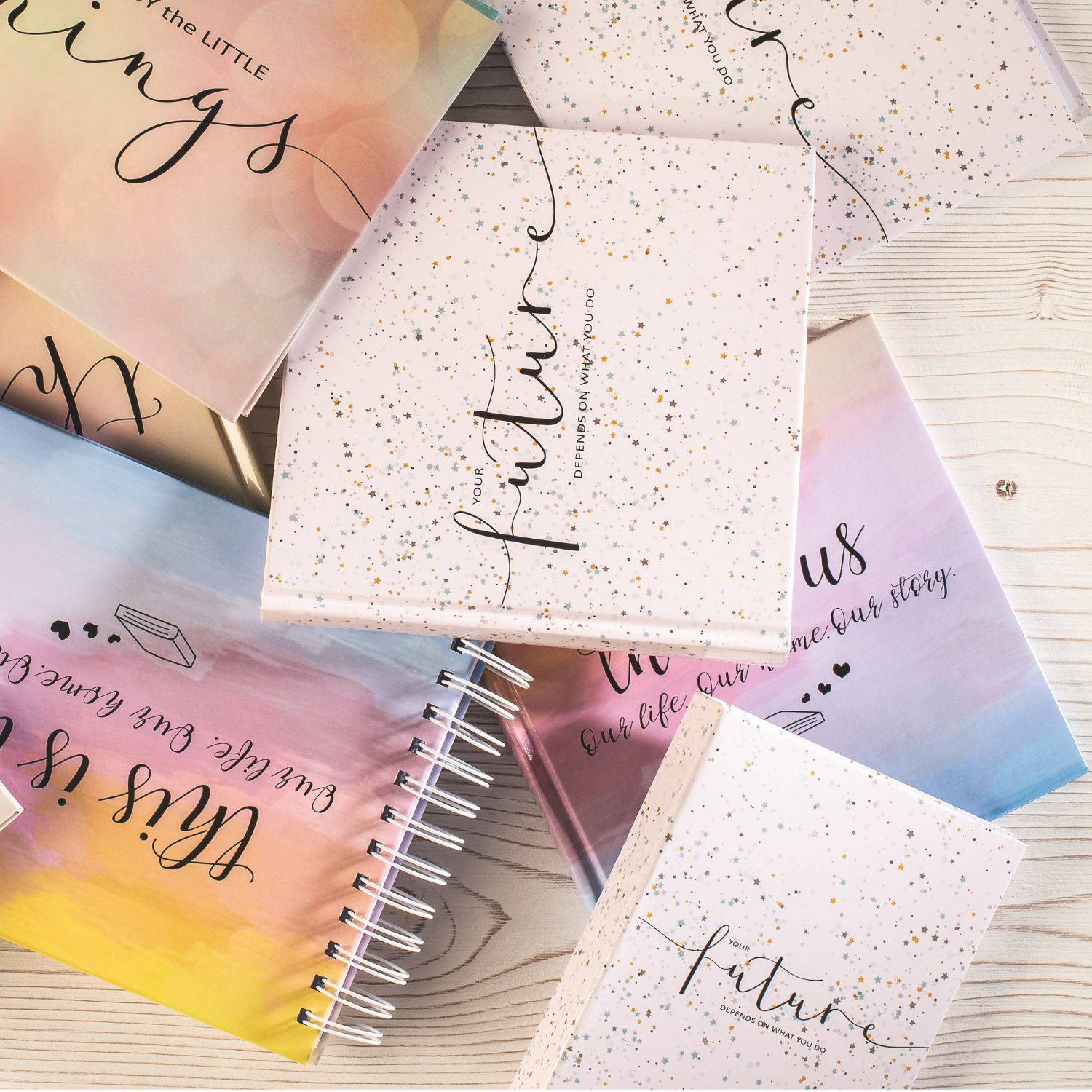 Kilka notatników z inspirującymi cytatami i kolorowymi akwarelami.