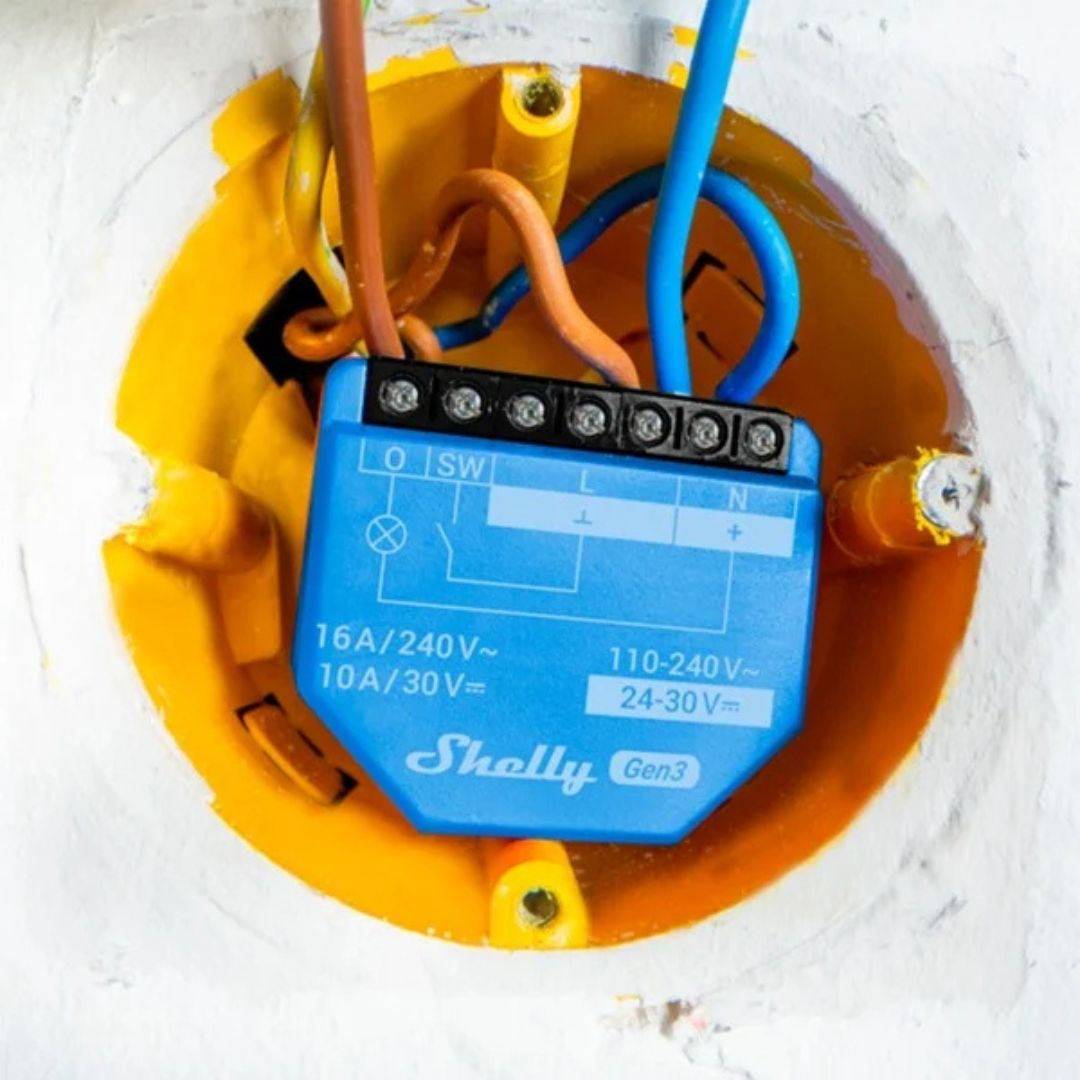 Niebieski przełącznik Shelly Gen3 jest podłączony w żółtej puszce elektrycznej.