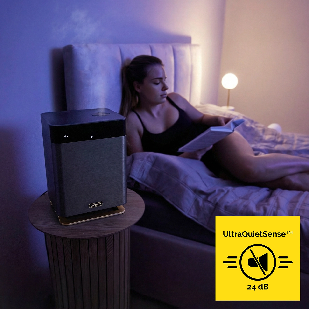 Kobieta czyta w łóżku, oczyszczacz powietrza na stoliku nocnym.