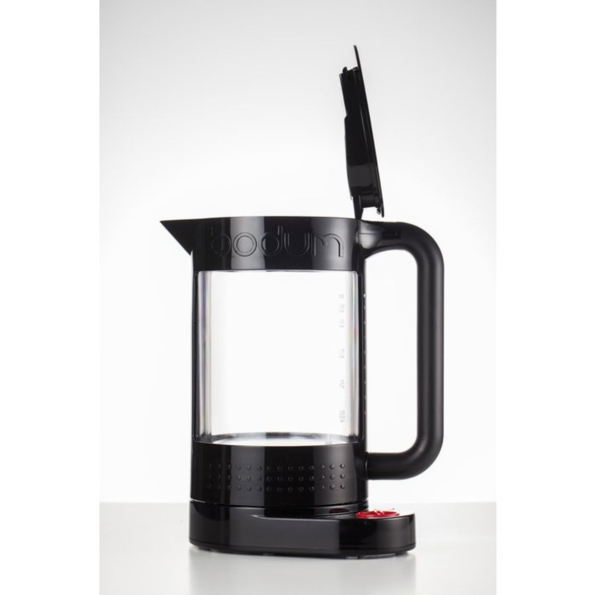 Schwarzer Wasserkocher mit Glaszylinder und offenem Deckel auf weißem Tisch.