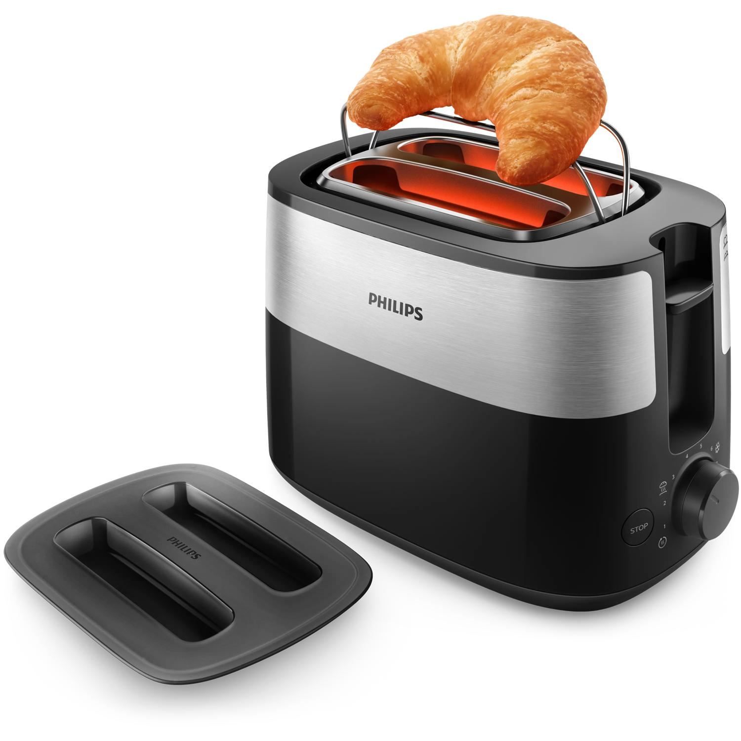 Ein schwarzer und silberner Philips-Toaster mit einem darin toastenden Croissant. Daneben eine Krümelschale.