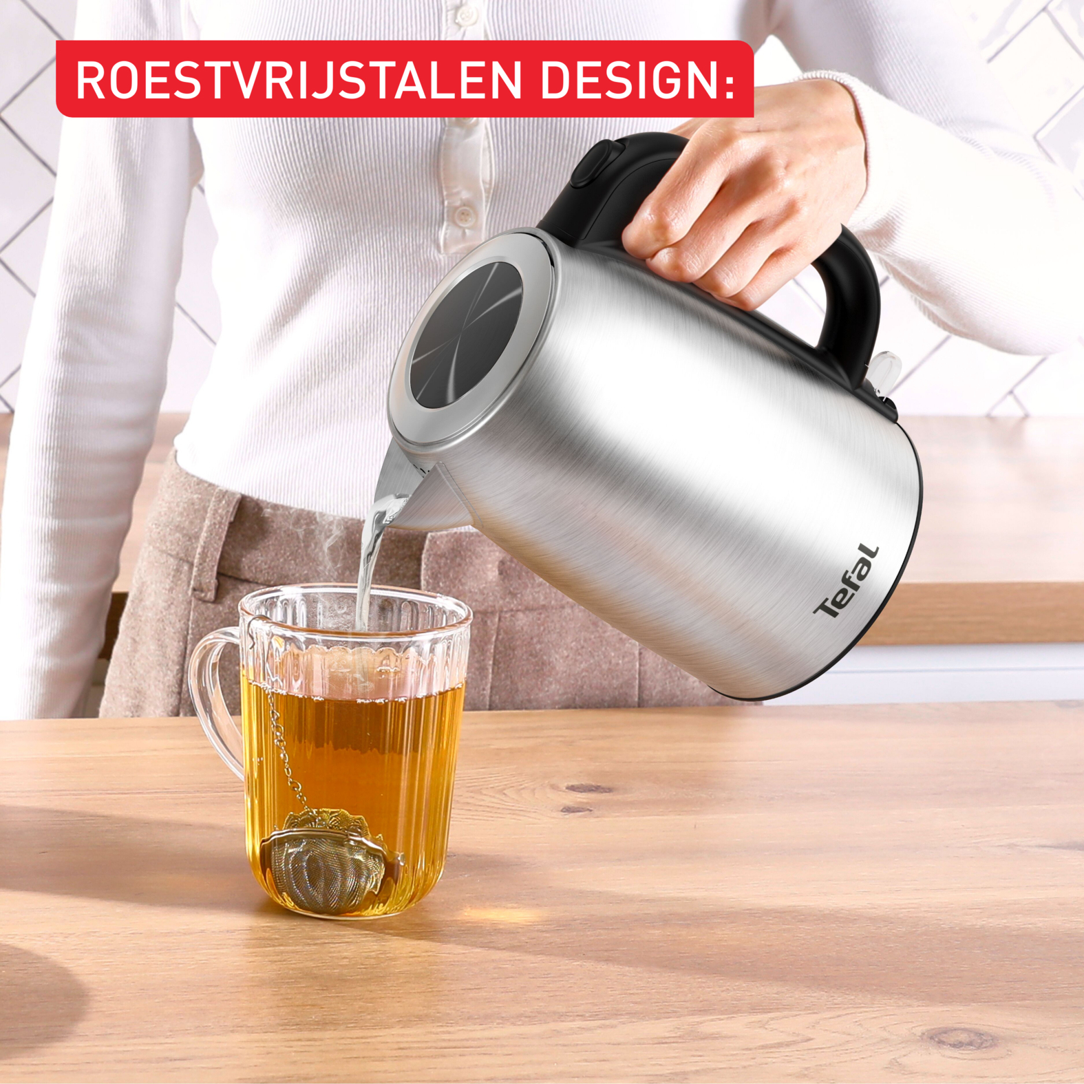Eine Person gießt mit einem Wasserkocher Wasser in eine Teetasse mit einem Tee-Ei.
