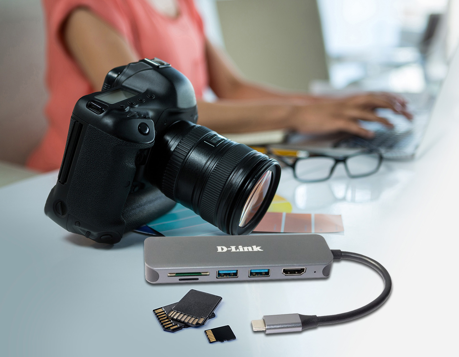 Eine Digitalkamera, ein USB-Hub und Speicherkarten liegen auf einem Schreibtisch.