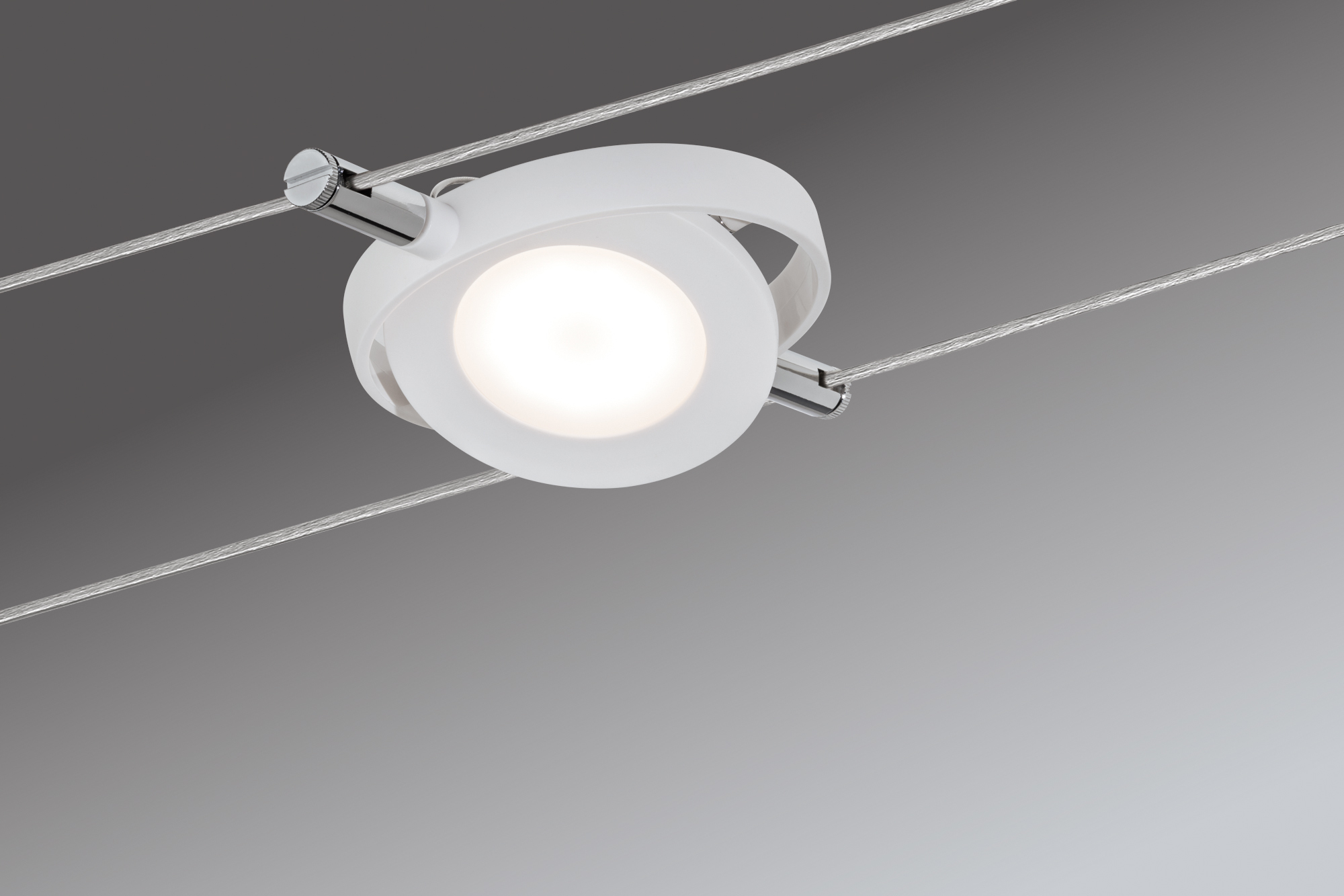 Un faretto rotondo bianco con dettaglio cromato, sospeso su due cavi sottili.