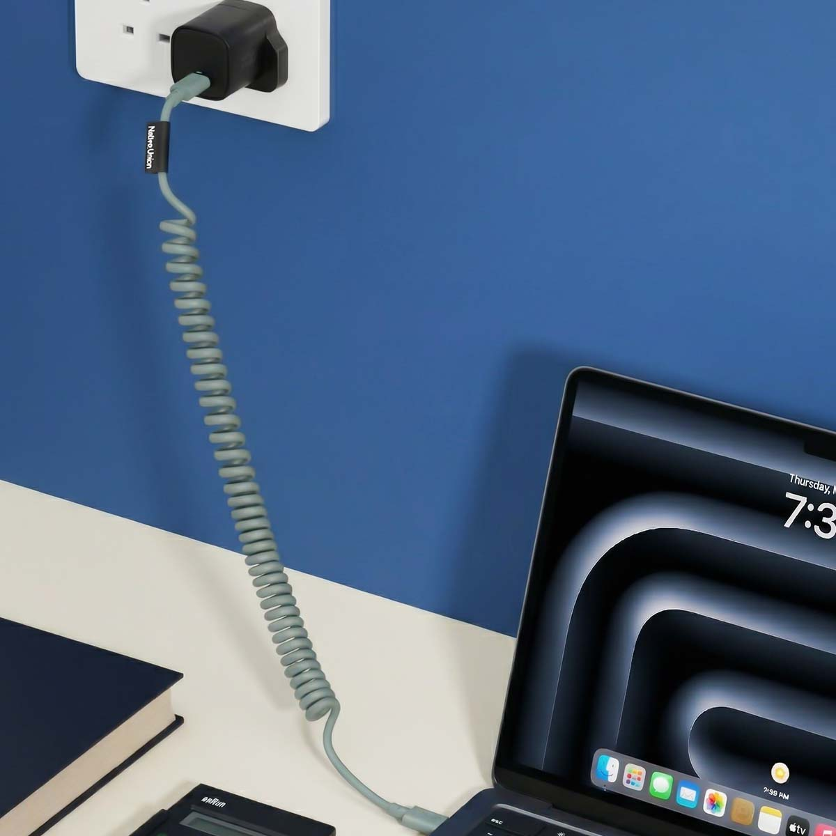 Un cavo grigio a spirale collega un alimentatore a un laptop.