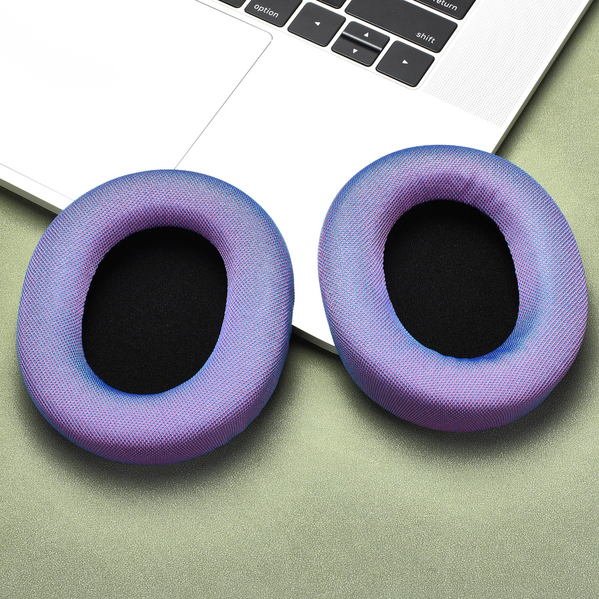 Due cuscinetti auricolari colorati riposano sulla tastiera di un laptop.