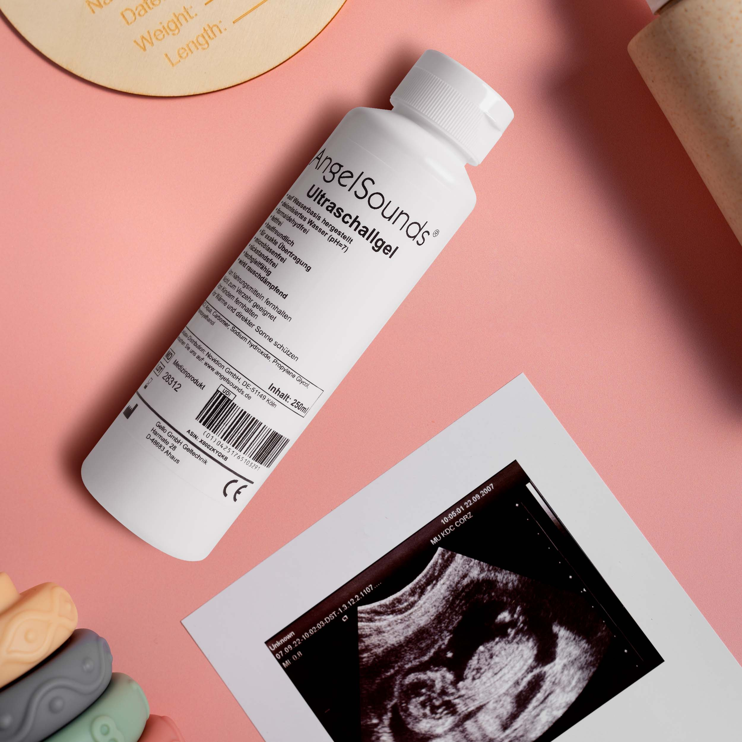 Ein Ultraschallgel und ein Baby-Ultraschallbild auf rosa Untergrund.