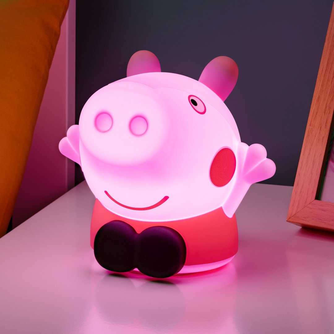 Różowa lampka Świnka Peppa świeci na białej powierzchni, z poduszką i ramką w pobliżu.