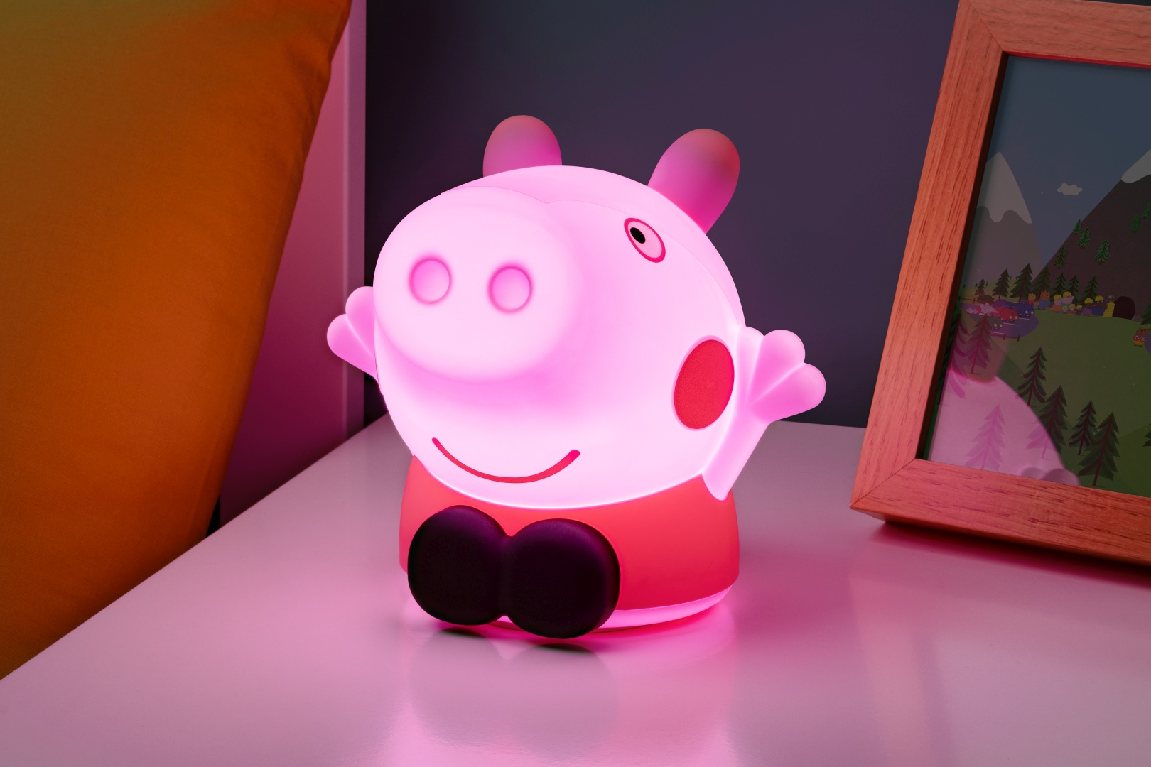 Świecąca lampka Świnka Peppa na szafce nocnej obok ramki na zdjęcie.