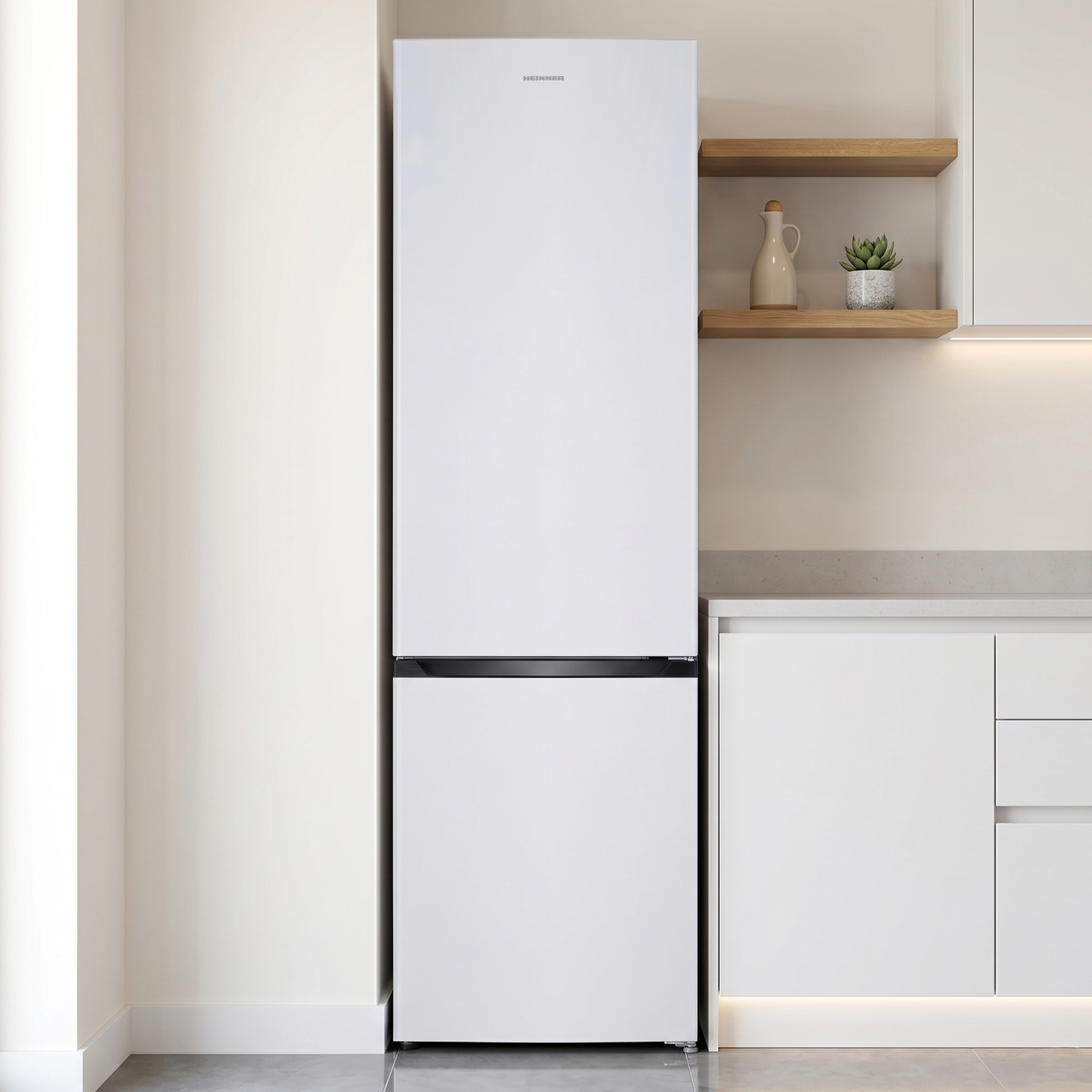 Ein weißer Kühlschrank steht in einer modernen Küche neben weißen Schränken.