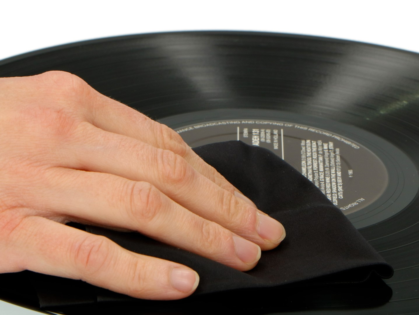 Dłoń czyści czarną szmatką płytę winylową.