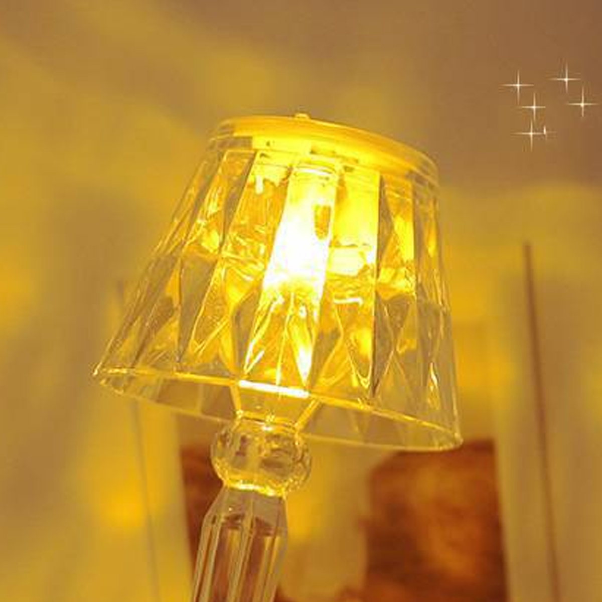 Eine transparente Lampe mit facettiertem Lampenschirm und warmem Licht.