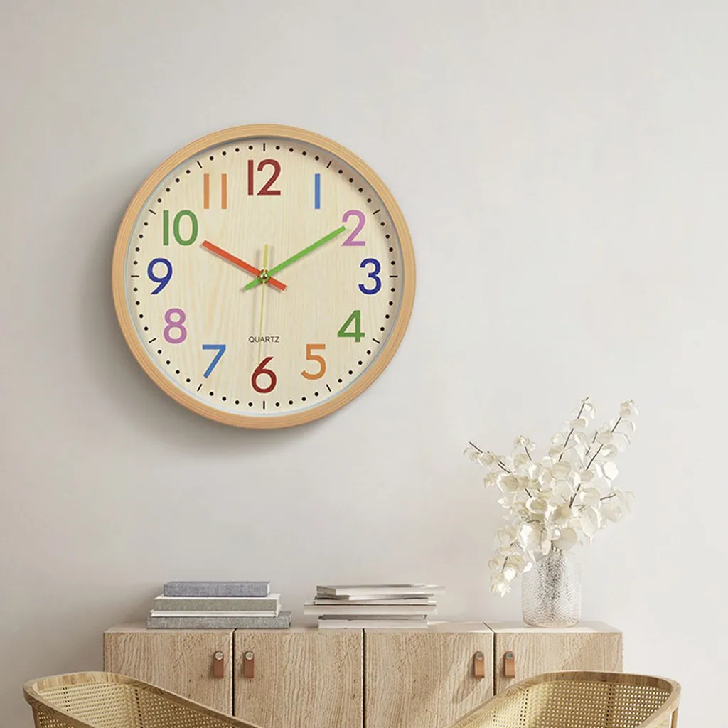 Eine runde Wanduhr mit bunten Ziffern auf hellem Holz ziert die Wand.