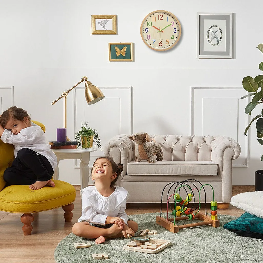 Zwei junge Mädchen spielen auf einem Teppich in einem Wohnzimmer mit einem beigen Sofa.