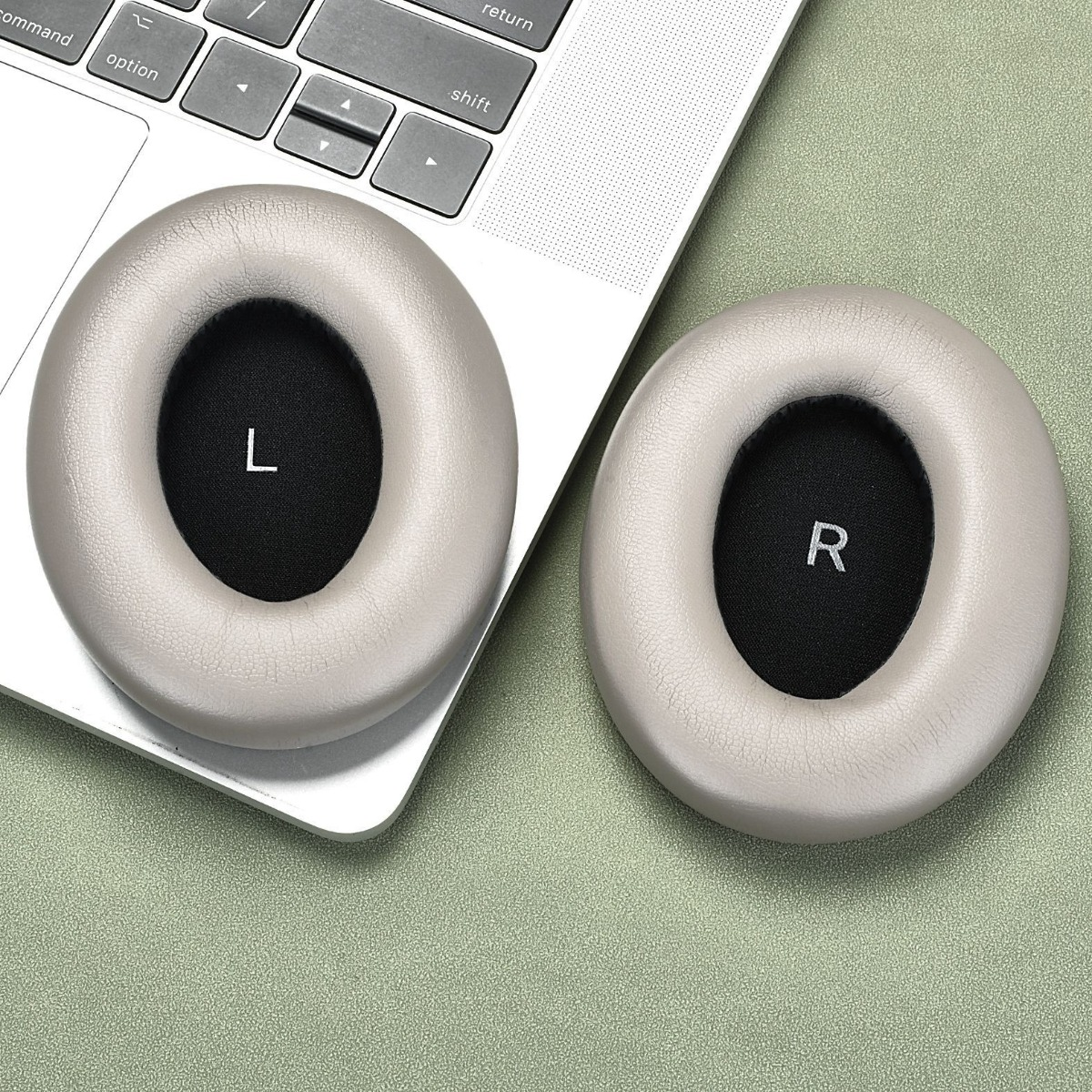 Zwei Ohrpolster für Kopfhörer, L und R, auf einer Tastatur.
