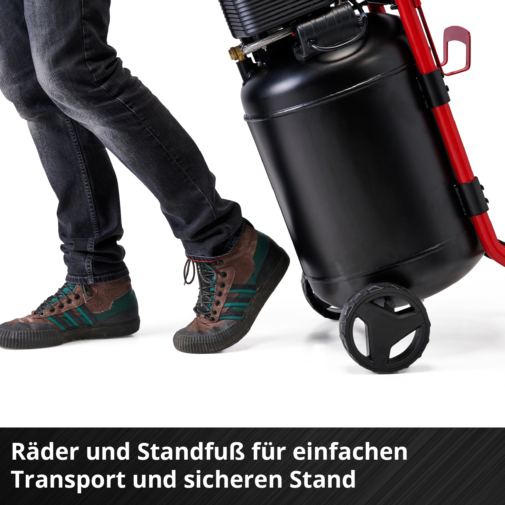 Person schiebt schwarzen Kompressor auf Rädern mit rotem Gestell.