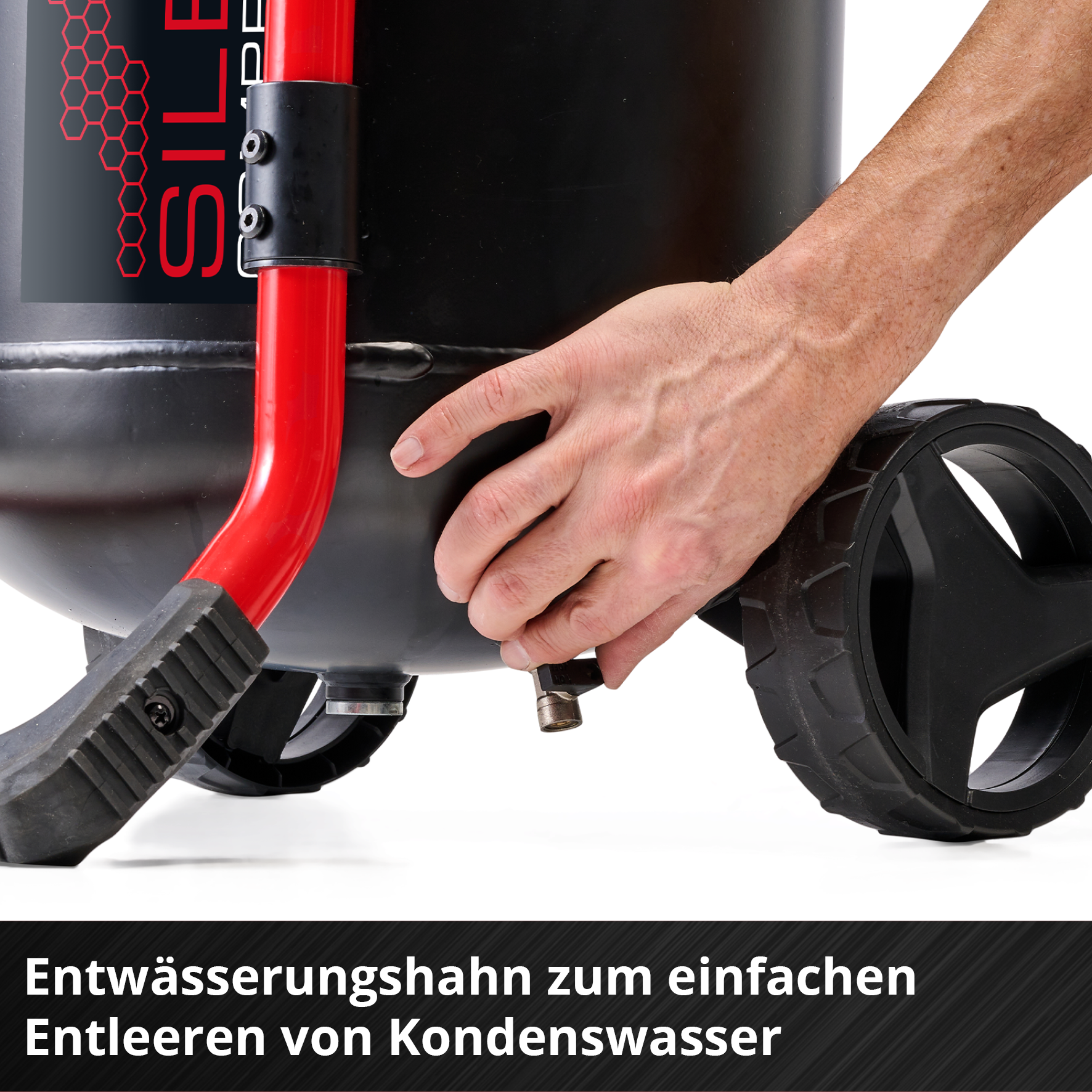 Ein Mann betätigt einen Ablasshahn an einem schwarzen Kompressor mit roten Rohren.