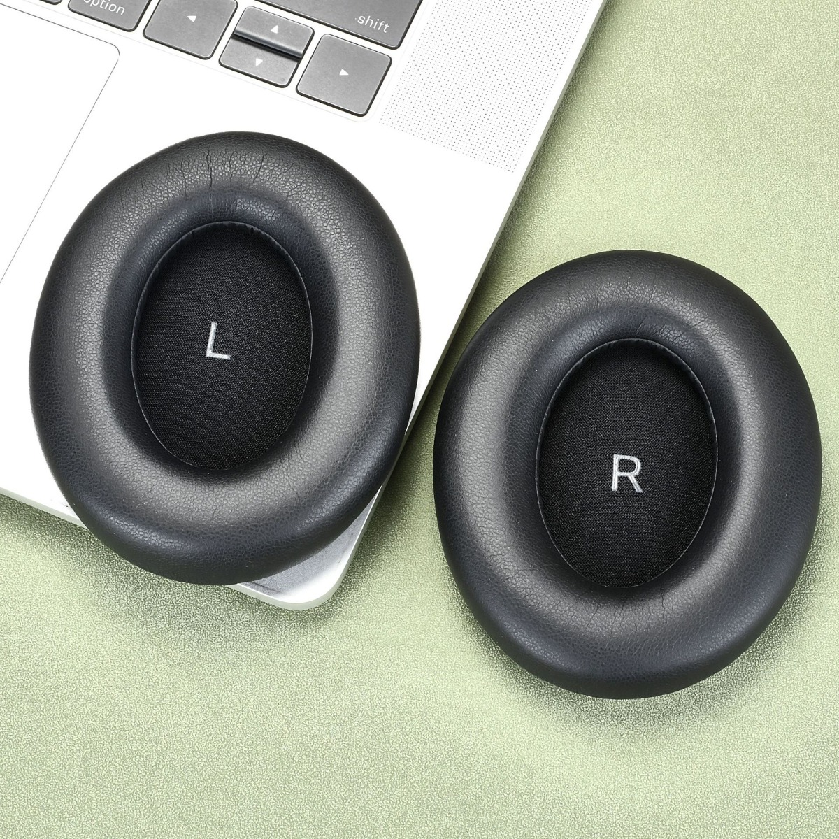 Due cuscinetti neri in pelle per cuffie, uno contrassegnato 'L', l'altro 'R', su un laptop.