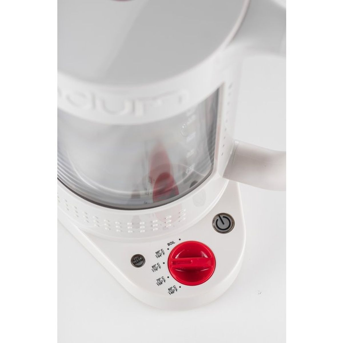 Un hervidor blanco con dial rojo y ajustes de temperatura.