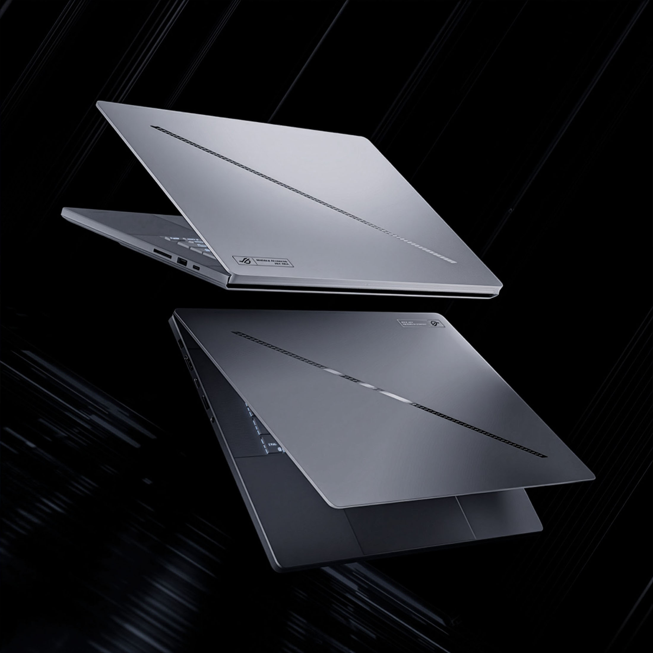Zwei silberne Laptops mit geschlossenen Deckeln auf schwarzem Hintergrund.